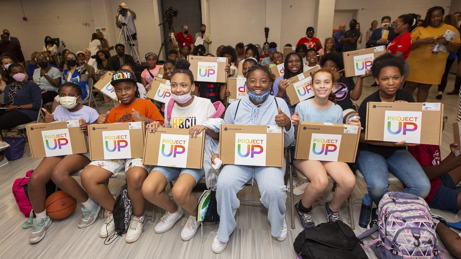 Students receive free laptops at a Project UP event.