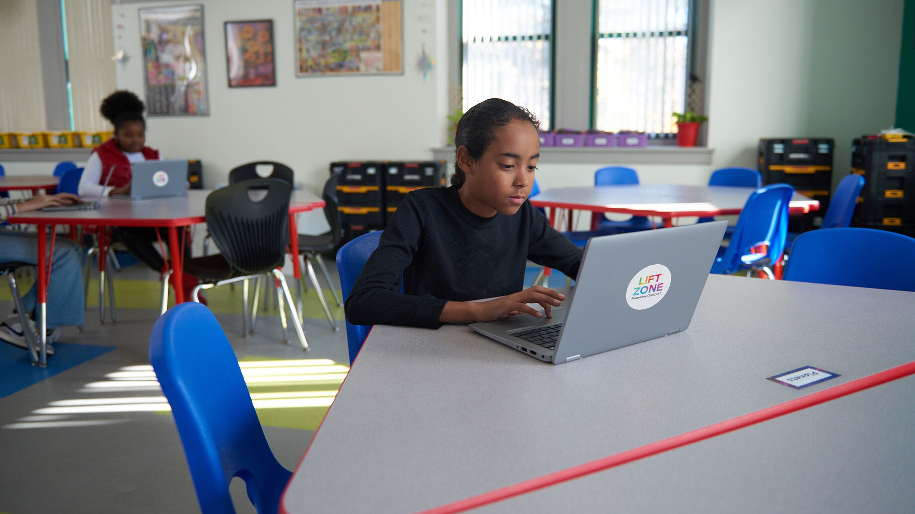 A student sitting at a table using a laptop.