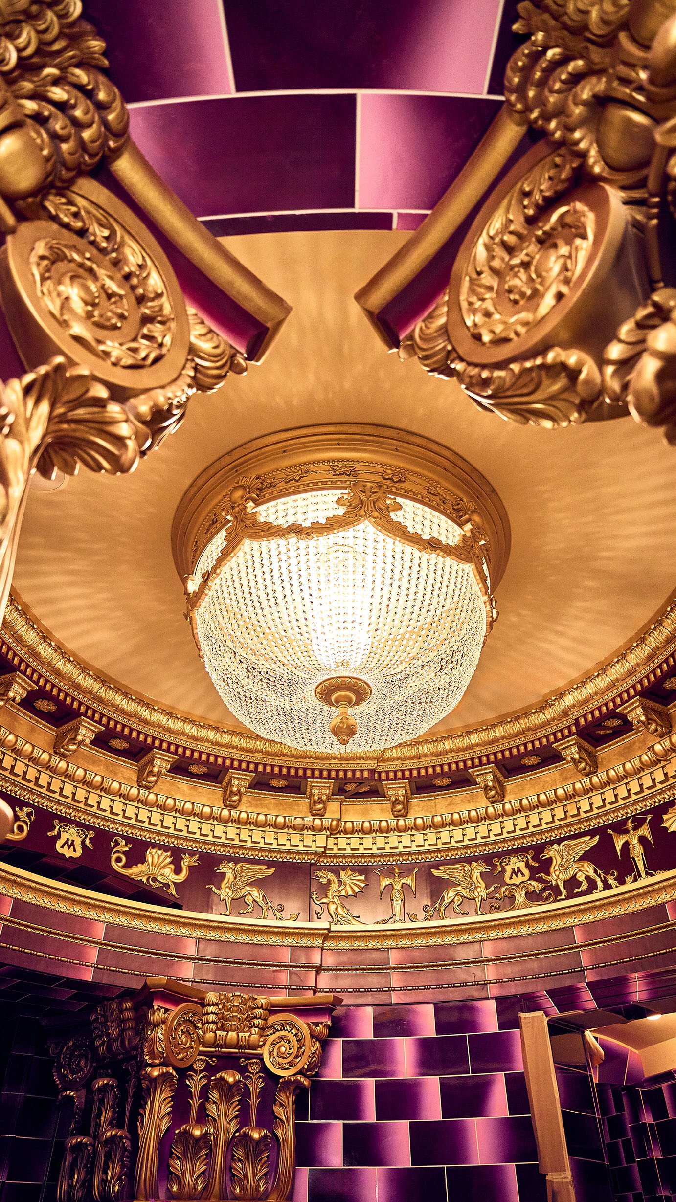 A glittering chandelier illuminates the former office of Dolores Umbridge™ at the British Ministry of Magic™. The tiled walls (pink, naturally) and ornate gold-colored carvings can be seen by guests e