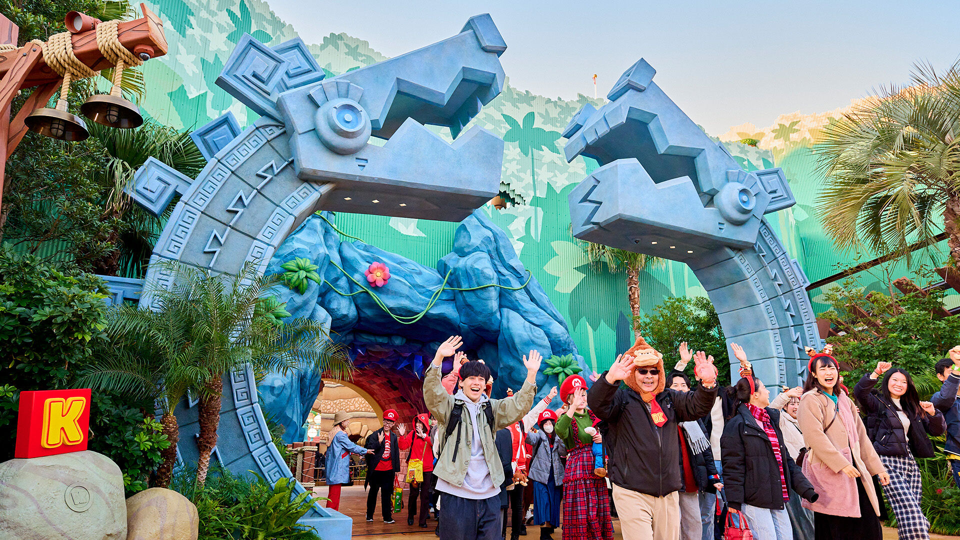 A large group of park patrons walking through the gates of Donkey Kong Country Area in Super Nintendo World.